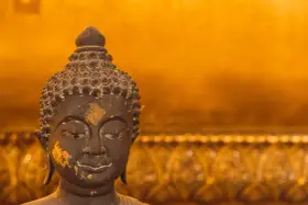 Buddhas ansikte med guldfolierester, en påminnelse om lugn under regnperioden i Asien.